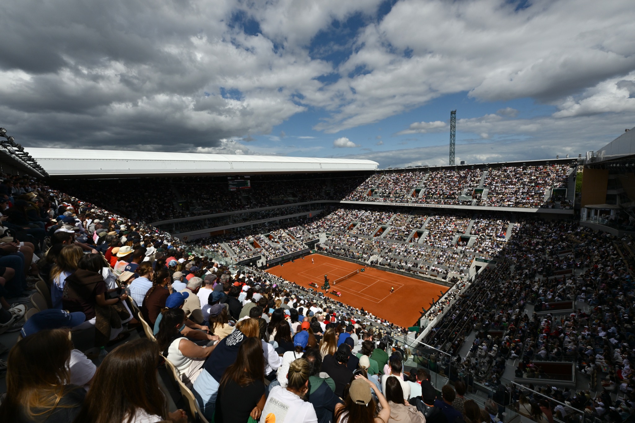 A full Roland Garros stadium beneath a dramatic sky